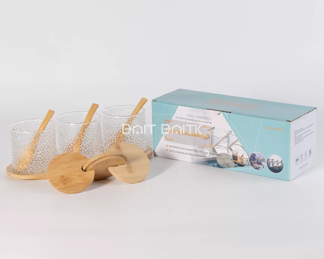 ثلاث علب سكريات زجاج مُحبّب مع أغطية بامبو وملاعق على قاعدة بامبو – تنظيم أنيق